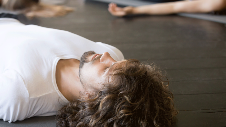 Man lying asleep on his yoga mat during Savasana