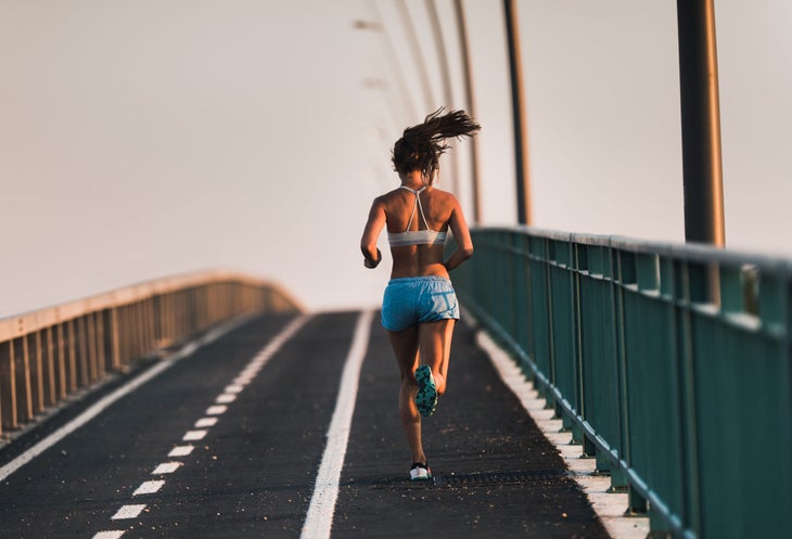 Runner on a bridge wearing shorts and a sports bra with tight hips